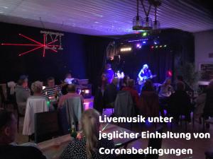 una multitud de personas sentadas en una habitación con una banda en un escenario en Ferienpark-Canow, en Canow