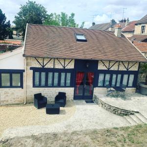 ein Haus mit schwarzen Stühlen und einer Terrasse in der Unterkunft Le cottage du clos des Forges in Saint-Leu-dʼEsserent