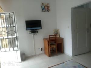 Habitación con TV, silla y escritorio. en Residences Hotels Sejours Affaires, en Abiyán