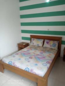 Cama en habitación con pared de rayas verdes y blancas en Residences Hotels Sejours Affaires, en Abiyán