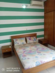 a bed in a room with green and white stripes at Residences Hotels Sejours Affaires in Abidjan