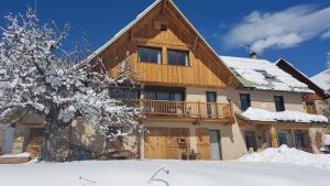 uma casa de madeira com um deque na neve em Chalet la Forestière em Orcières