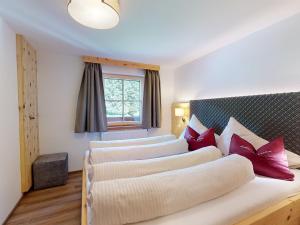 a bedroom with three beds with red pillows at Erbhof Hinterrain in Leogang