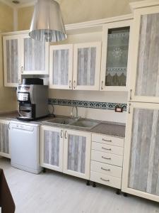cocina con armarios blancos, fregadero y microondas en B&B Desenzano, en Desenzano del Garda