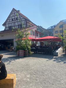 une personne assise sur un banc devant un bâtiment dans l'établissement Hotel Boutique Taverne zum Kreuz, à Winterthour