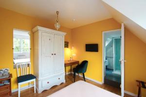 um quarto com paredes amarelas, uma secretária e uma cadeira. em A la Maison du Héron em Villeneuve d'Ascq