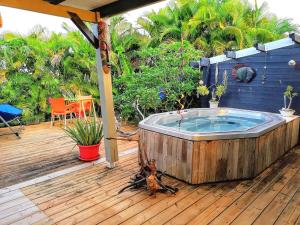 a hot tub sitting on a wooden deck at Bungalow La Perle - Jacuzzi - Piscine in Saint-François