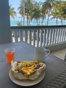 a slice of pizza on a plate on a table with a coffee cup at Cozy Beach Apartment in Luquillo