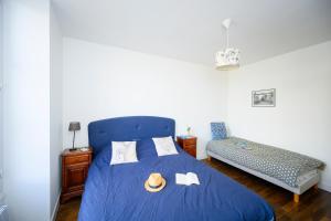 Saint-Dyé-sur-LoireにあるLa Boisseléeのベッドルーム1室(青いベッド1台、帽子、タオル付)