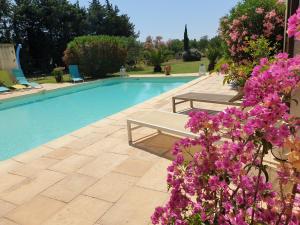 een zwembad met twee banken en paarse bloemen bij LAGREMUSE in Sarrians