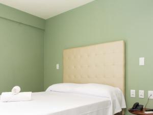a bedroom with a white bed and green walls at Ilusion Hotel in Natal