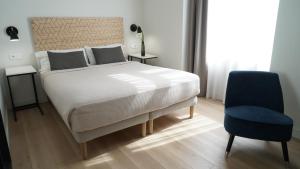 um quarto com uma cama e uma cadeira azul em MD Design Hotel - Portal del Real em Valência