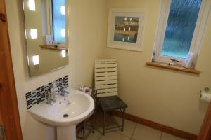 a bathroom with a sink and a mirror and a chair at Corunna Cottage in Inverness +12 photos