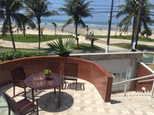eine Terrasse mit Tisch und Stühlen sowie Strand in der Unterkunft Apto. De frente pro Mar in Praia Grande