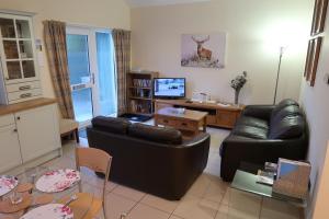 a living room with two leather couches and a television at Corunna Cottage in Inverness