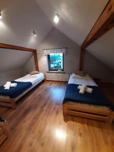 a attic bedroom with two beds and a window at Zielona Mila Dom Wakacyjny in Cekcyn