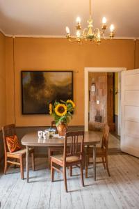 a dining room with a table with a vase of sunflowers at Roberta Hercberga Apartamenti in Kuldīga