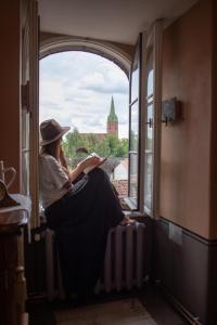 uma mulher sentada numa janela a ler um livro em Roberta Hercberga Apartamenti em Kuldīga