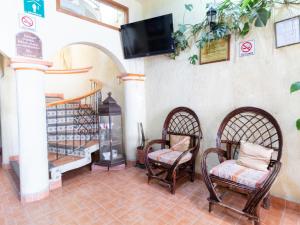 a room with two chairs and a tv on the wall at Hotel Villa Real II in San Crist&oacute;bal de Las Casas