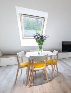 een eettafel met gele stoelen en een vaas met bloemen bij Botanical garden apartment in Kaunas