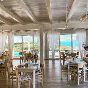 a dining room with tables and chairs and windows at Casamediterranea in Sperlonga