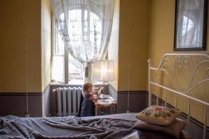 a little girl standing in a bedroom looking out the window at Roberta Hercberga Apartamenti in Kuldīga