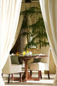 mesa de comedor con sillas y cortinas blancas en Baraza Resort and Spa Zanzibar en Bwejuu