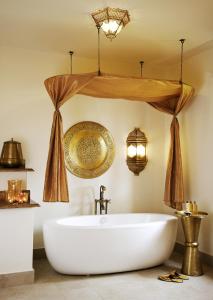 a bathroom with a tub and a chandelier at Baraza Resort and Spa Zanzibar in Bwejuu