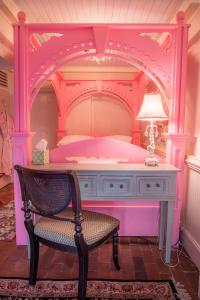 a pink bed with a table and a chair at Justine Inn Savannah in Savannah