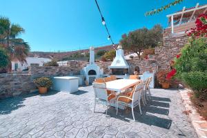 un patio con una mesa, sillas y una fuente. en Antiparos View, en Antíparos