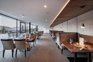 a restaurant with wooden tables and chairs and windows at Hotel Edelweiss in Maranza