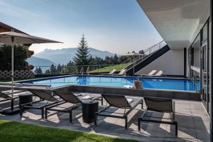 a swimming pool with chairs and a house at Hotel Edelweiss in Maranza