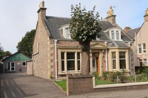 a house with a tree in front of it at Corunna Bed & Breakfast and Garden Cottage in Inverness