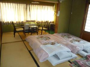 - 2 lits dans une chambre avec une table et des chaises dans l'établissement Uotoshi Ryokan, à Yamanouchi