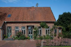 een stenen huis met een rood dak bij HausAltenkamp in Bad Zwischenahn