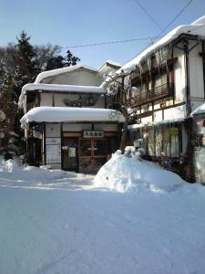 une maison avec un tas de neige devant elle dans l'établissement Uotoshi Ryokan, à Yamanouchi