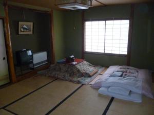 a bedroom with a bed and a tv in it at Uotoshi Ryokan in Yamanouchi
