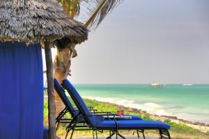 a beach with chairs and an umbrella and the ocean at The Palms Zanzibar in Bwejuu