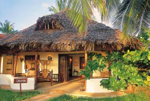 een huis met een rieten dak en een palmboom bij The Palms Zanzibar in Bwejuu