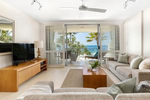 a living room with a couch and a tv at Fairshore 22 Main Beach Views in Noosa Heads
