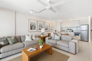 a living room with two couches and a kitchen at Fairshore Apartment 22, Noosa Heads in Noosa Heads