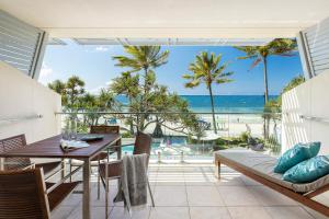 a dining room with a table and chairs and the beach at Fairshore 22 Main Beach Views in Noosa Heads