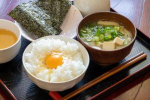 ein Tablett mit Reis und einem Ei und einer Schüssel Suppe in der Unterkunft Guest House Fuku-chan in Kaiyo