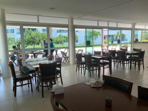 a restaurant with tables and chairs and a view of the ocean at Flat Carneiros Beach Resort in Tamandaré