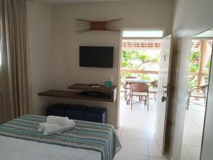 een slaapkamer met een bed, een bureau en een televisie bij Dunas de Marape in Jequiá da Praia