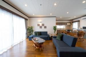 a living room with blue couches and a kitchen at with-terrace (Umi) in Kohama