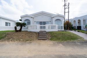 una casa blanca con una palmera delante de ella en with-terrace (Umi), en Kohama