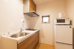 a small kitchen with a sink and a microwave at GRAND BASE Hakata Gofuku in Fukuoka