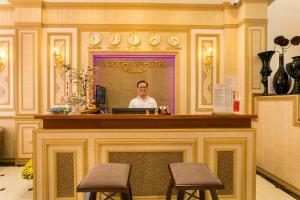 a man sitting at a reception desk with two stools at Indochine Ben Thanh Hotel & Apartments in Ho Chi Minh City