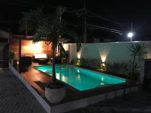 una piscina notturna con una palma di Flats de Sumatra a Boicucanga